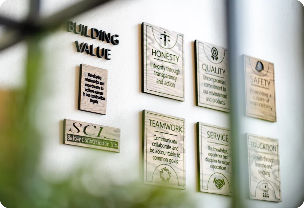 A wall display features plaques with the heading Building Value and values like honesty, quality, safety, teamwork, service, and education, plus an SCL Salter Construction Inc. plaque.